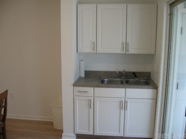 kitchen with white cabinets, wood-type flooring, and sink