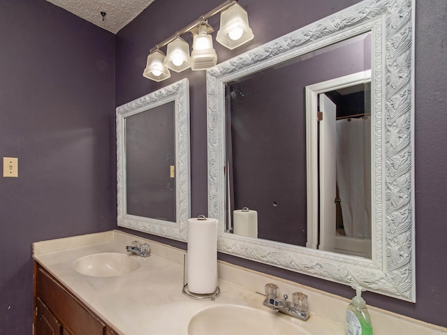 bathroom featuring curtained shower, vanity, and a textured ceiling