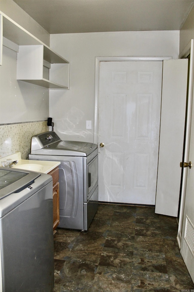 washroom with stone finish floor, visible vents, and washer and clothes dryer