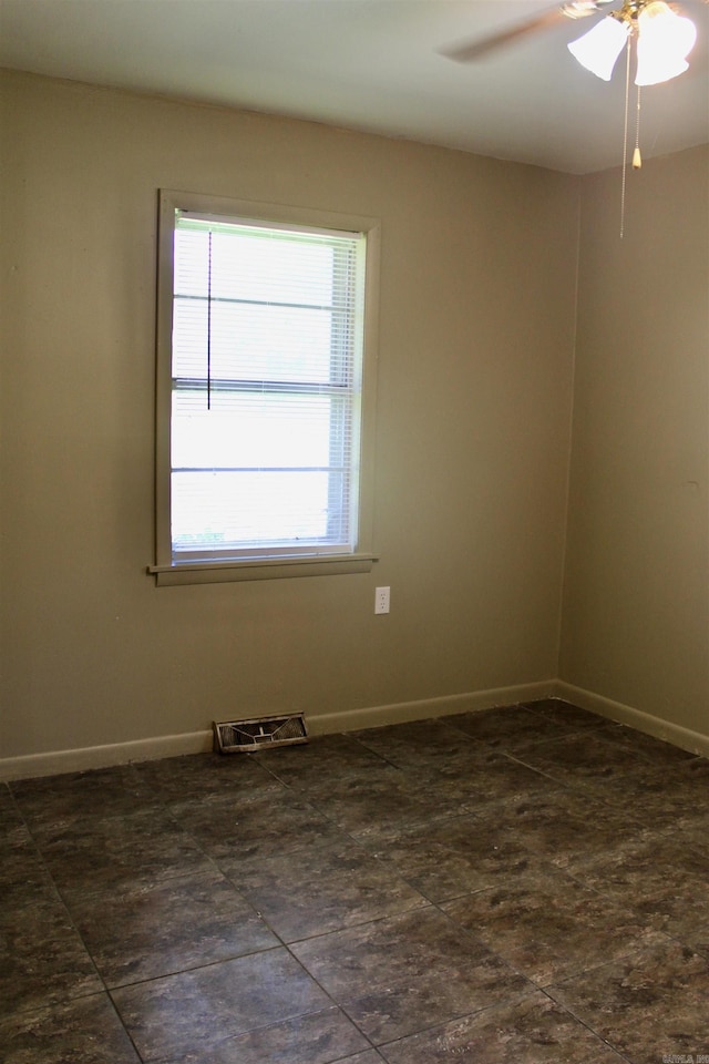 empty room featuring ceiling fan, visible vents, and baseboards