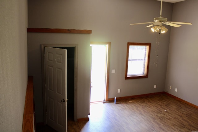 unfurnished room with wood finished floors, a ceiling fan, and baseboards