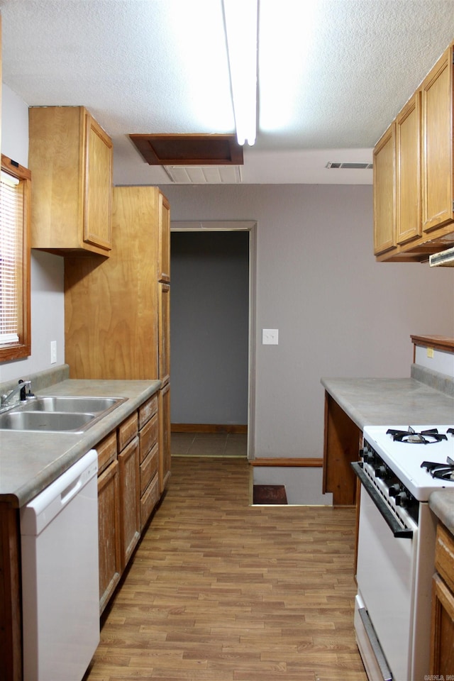 kitchen featuring a textured ceiling, white appliances, a sink, light wood-style floors, and light countertops