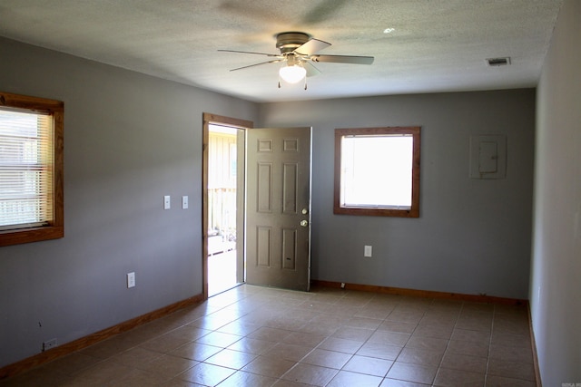 tiled spare room with a ceiling fan, visible vents, a textured ceiling, and baseboards