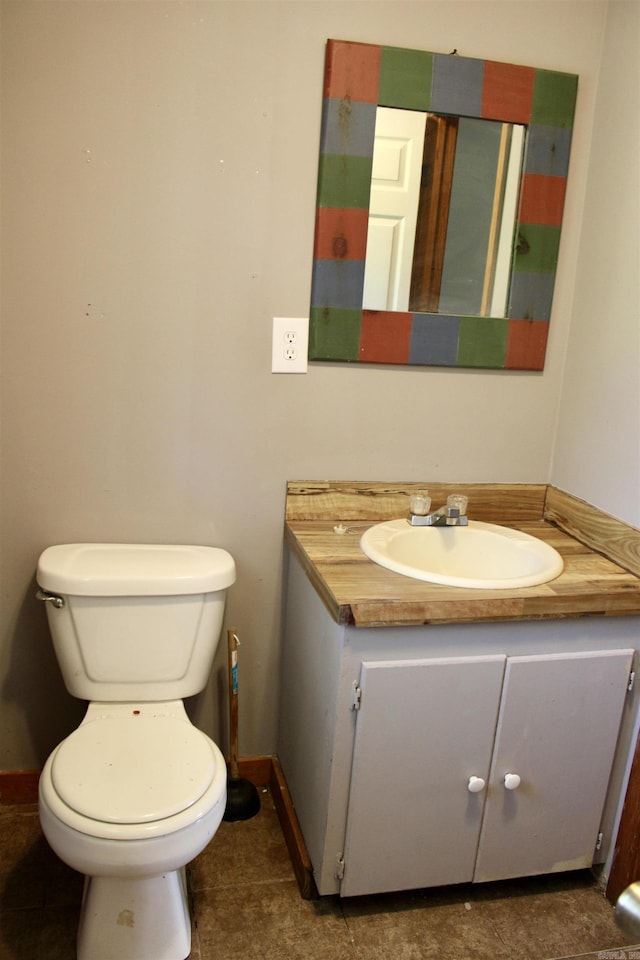 half bath featuring baseboards, vanity, and toilet