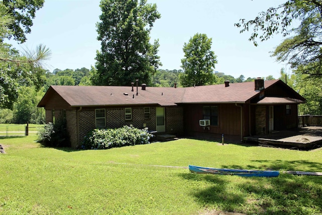 rear view of property featuring a yard, brick siding, a chimney, and cooling unit