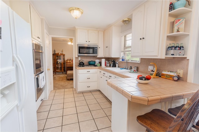 kitchen with backsplash, appliances with stainless steel finishes, sink, and kitchen peninsula