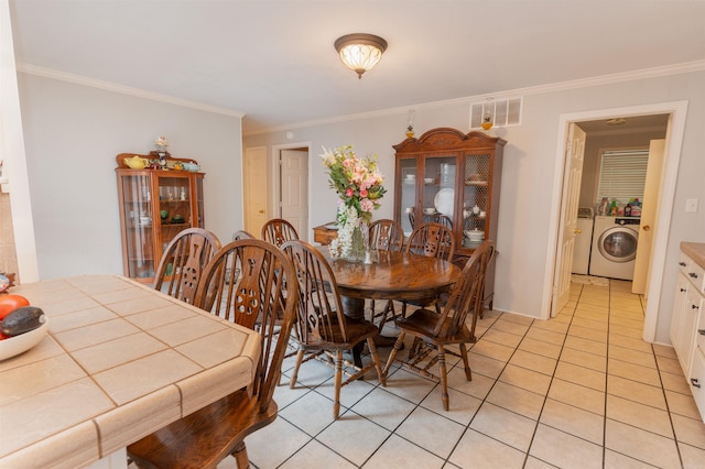 tiled dining space with washer and dryer and ornamental molding