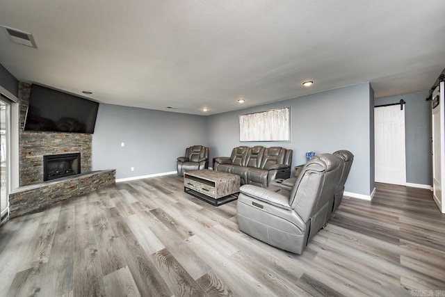 living room featuring a barn door, a fireplace, and wood-type flooring