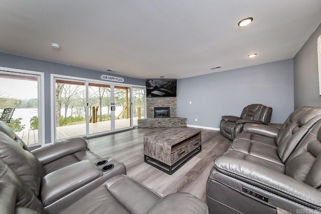 living room with a stone fireplace and hardwood / wood-style flooring