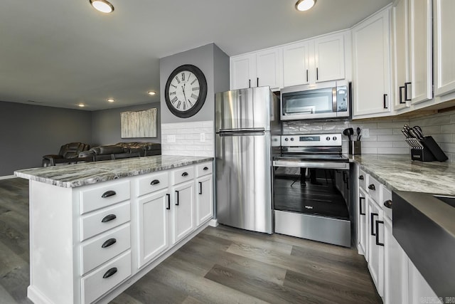 kitchen with white cabinets, appliances with stainless steel finishes, tasteful backsplash, and hardwood / wood-style floors