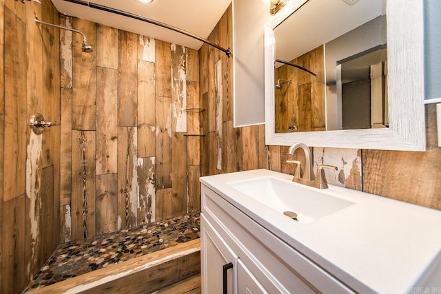 bathroom featuring walk in shower, wood walls, and vanity