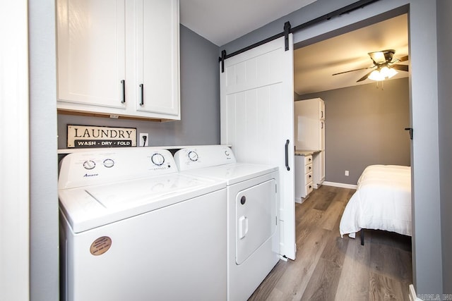 washroom featuring separate washer and dryer, cabinets, light wood-type flooring, a barn door, and ceiling fan