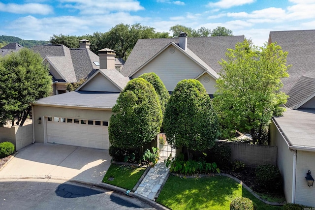 view of front of home with driveway, a garage, a shingled roof, a chimney, and fence