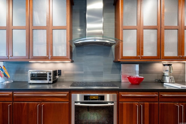 kitchen with a toaster, tasteful backsplash, oven, wall chimney exhaust hood, and black electric cooktop