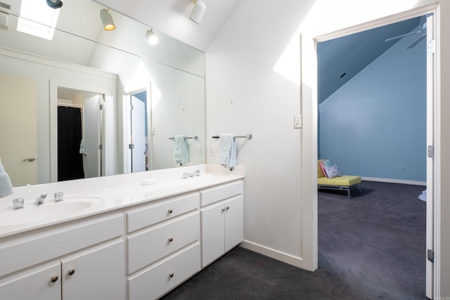 bathroom featuring baseboards, vaulted ceiling, a sink, and double vanity