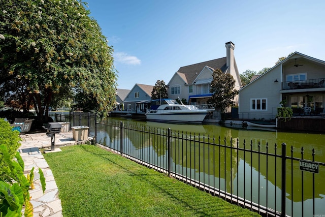 view of yard featuring a residential view, a water view, fence, and a patio