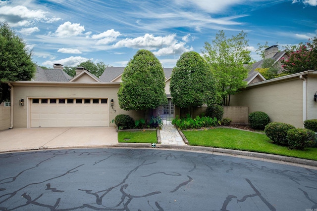 view of front facade featuring concrete driveway, a chimney, and an attached garage