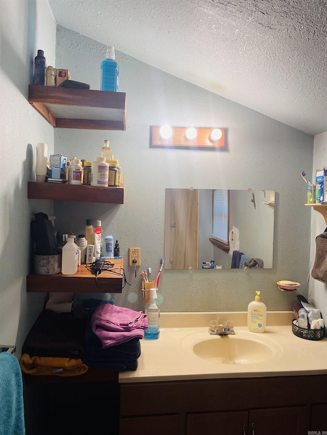 bathroom featuring vanity, lofted ceiling, and a textured ceiling