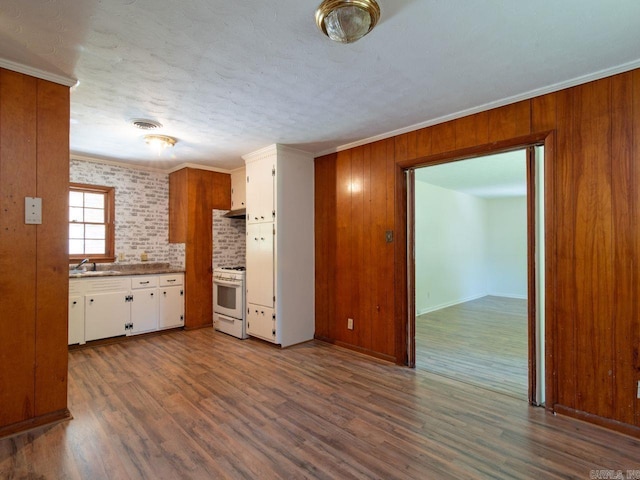 kitchen featuring white gas stove, dark hardwood / wood-style floors, white cabinetry, and tasteful backsplash