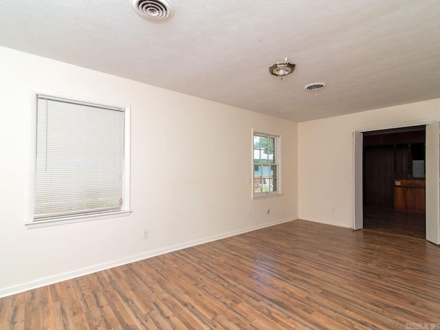 unfurnished room featuring dark wood-type flooring and a textured ceiling