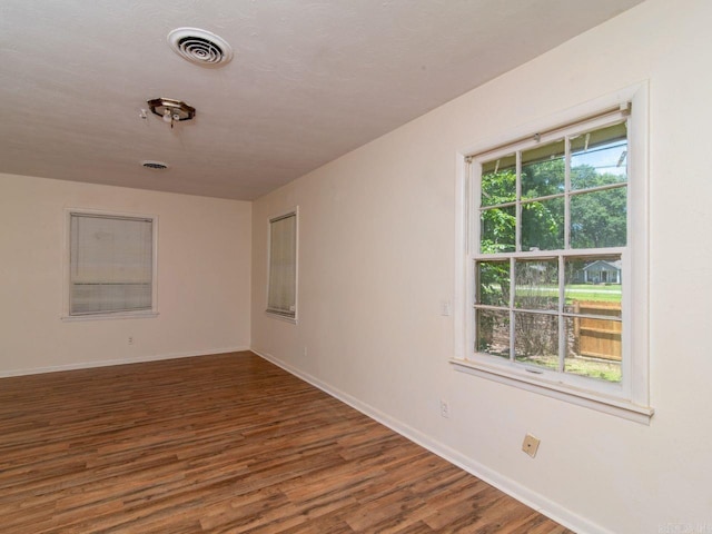 spare room with dark hardwood / wood-style flooring and a healthy amount of sunlight