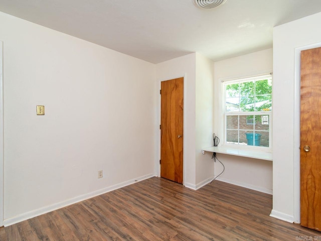 unfurnished room with dark wood-type flooring