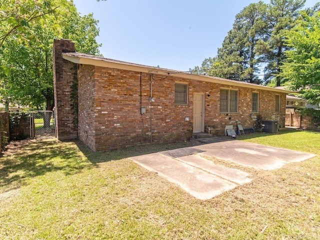 back of property with a lawn, a patio, and central AC