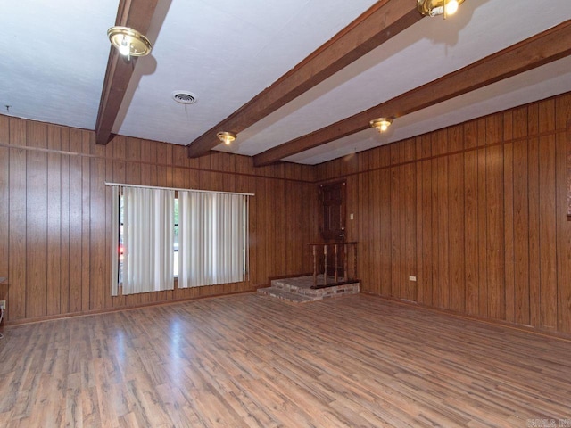 spare room featuring hardwood / wood-style flooring, wood walls, and beamed ceiling