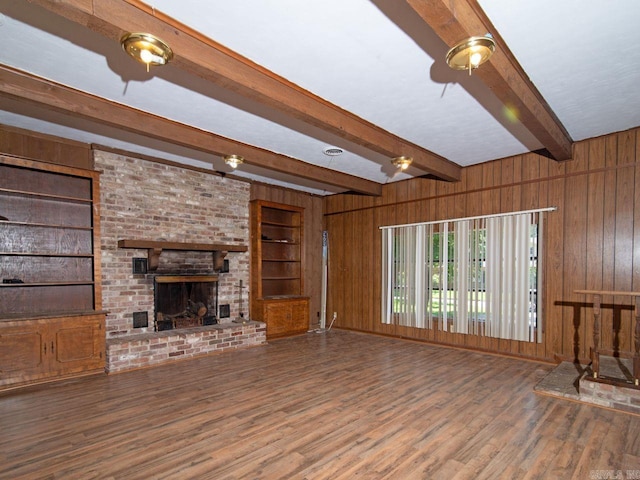 unfurnished living room featuring wooden walls, a fireplace, beamed ceiling, and hardwood / wood-style flooring