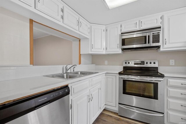 kitchen with appliances with stainless steel finishes, white cabinetry, sink, and dark wood-type flooring