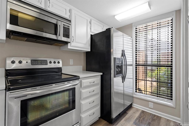 kitchen featuring stainless steel appliances, dark hardwood / wood-style flooring, and white cabinetry