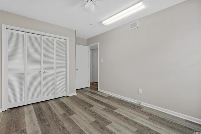 unfurnished bedroom with hardwood / wood-style flooring, ceiling fan, and a closet