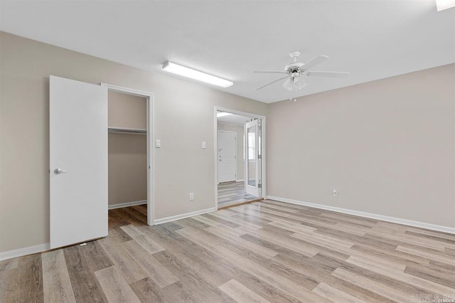 unfurnished bedroom with ceiling fan, a closet, light wood-type flooring, and a spacious closet