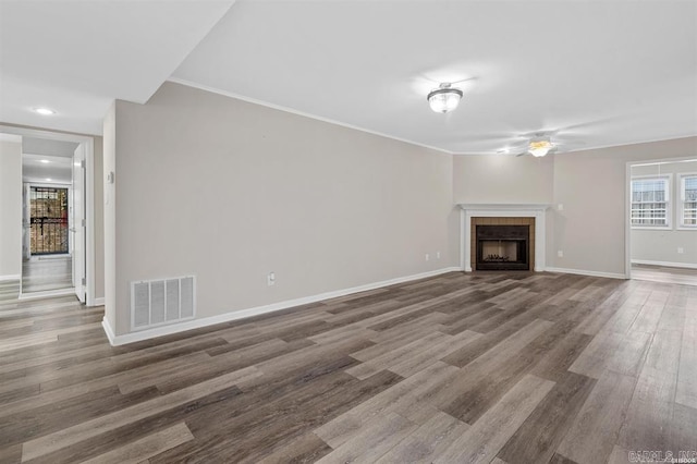 unfurnished living room with a tiled fireplace, hardwood / wood-style flooring, and crown molding