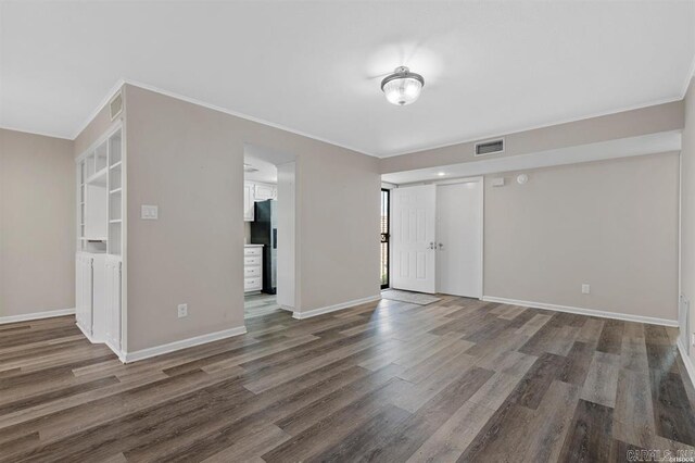 empty room with dark wood-type flooring and ornamental molding