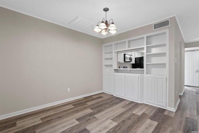 interior space with hanging light fixtures, black fridge, built in shelves, and wood-type flooring