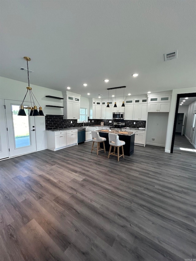 kitchen featuring decorative light fixtures, dark hardwood / wood-style floors, stainless steel appliances, white cabinetry, and a center island