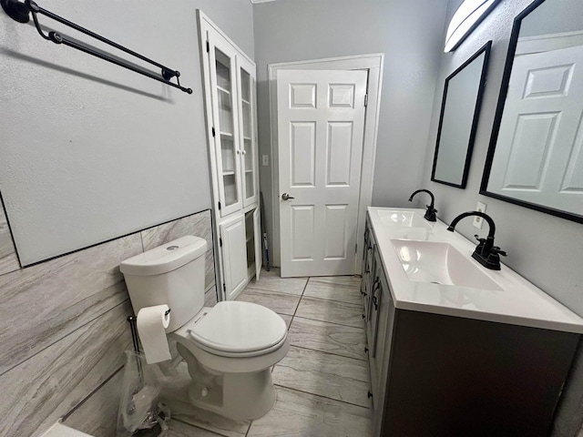 bathroom with vanity, toilet, and tile walls