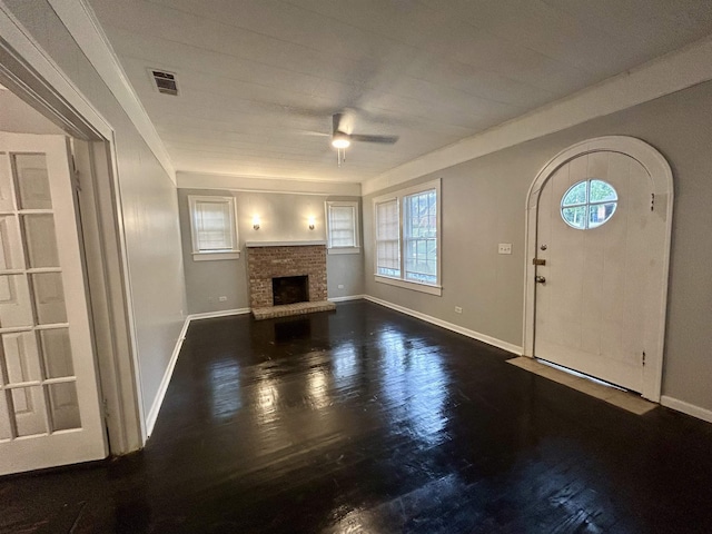 unfurnished living room featuring dark hardwood / wood-style flooring, a brick fireplace, ornamental molding, and ceiling fan