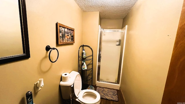 bathroom with an enclosed shower, a textured ceiling, and toilet