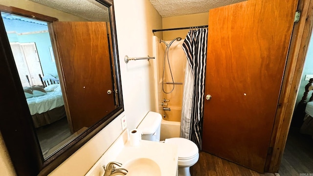 full bathroom featuring toilet, hardwood / wood-style floors, shower / bath combination with curtain, sink, and a textured ceiling