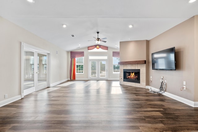 unfurnished living room with vaulted ceiling, ceiling fan, a tiled fireplace, and hardwood / wood-style flooring