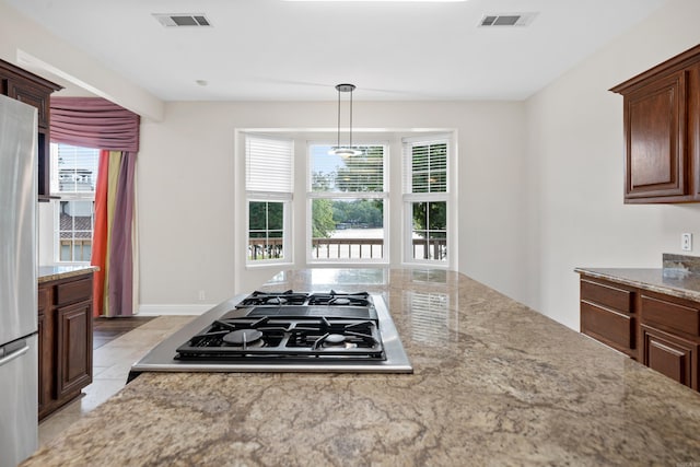 kitchen featuring hanging light fixtures, gas cooktop, stainless steel fridge, and light tile floors