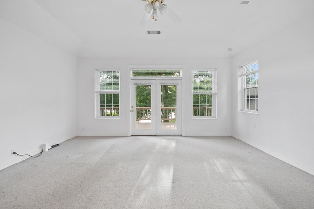 carpeted spare room with plenty of natural light, ceiling fan, and french doors