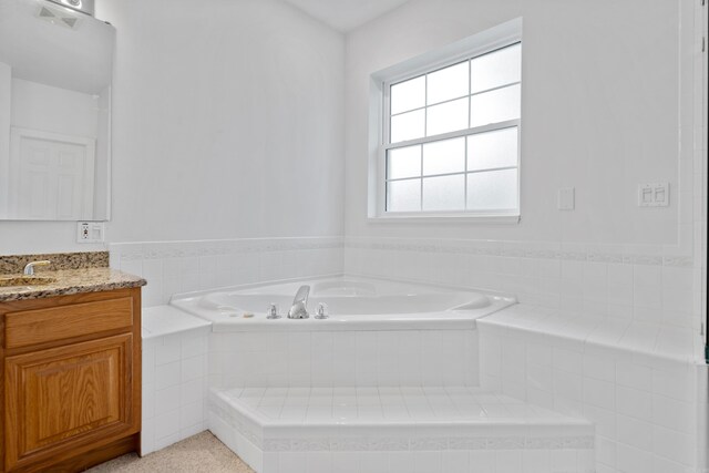 bathroom featuring tiled tub and vanity