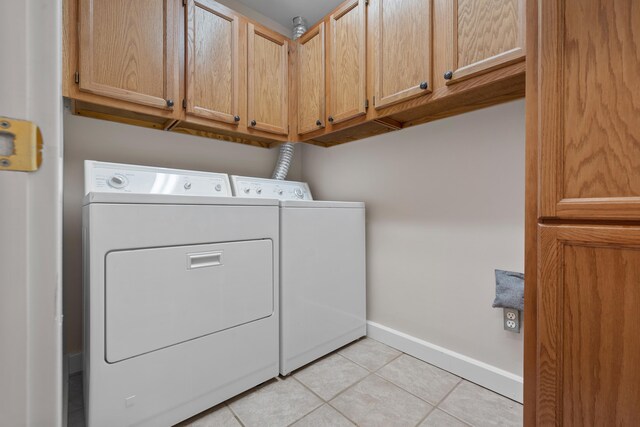 laundry area featuring cabinets, light tile flooring, and washer and clothes dryer