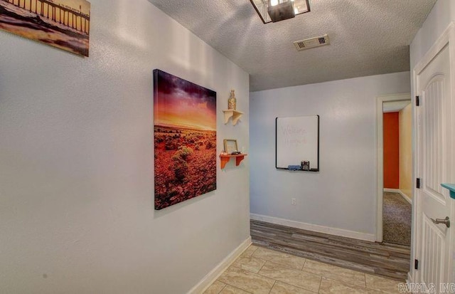 hallway with light tile patterned floors and a textured ceiling