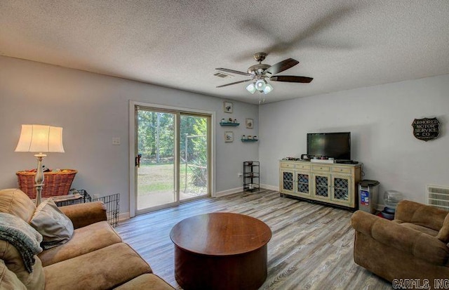 living room featuring a ceiling fan, a textured ceiling, baseboards, and wood finished floors