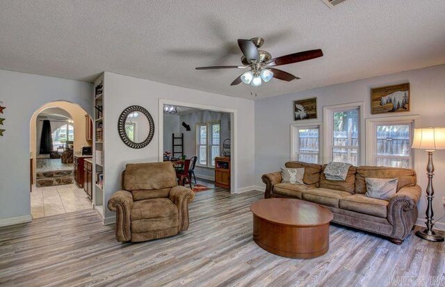 living room featuring wood-type flooring, a textured ceiling, and ceiling fan