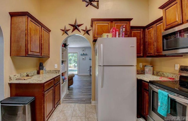 kitchen featuring light stone counters, light tile patterned floors, and stainless steel appliances